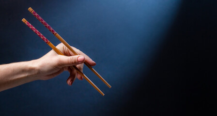 Hand holding japanese chopstick for sushi maki food. Traditional bamboo tool for oriental cuisine