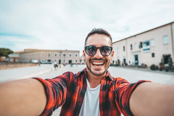 Handsome young man taking selfie on city street - Happy smiling guy portrait walking outdoors