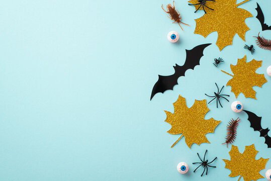 Halloween concept. Top view photo of gold glitter maple leaves bat silhouettes spooky eyeballs spiders cockroach and centipedes on isolated pastel blue background with copyspace