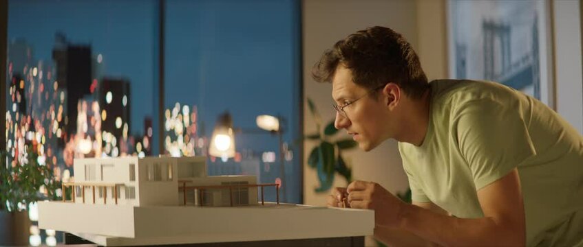 Portrait of Caucasian male architect or student working on a house project scale model late at home, preparing for presentation with a client