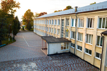 Aerial view of school, college or kindergarten building with big yard among autumn trees on rural landscape background