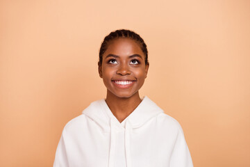 Photo of impressed young brunette lady with braids look up wear white hoodie isolated on beige color background