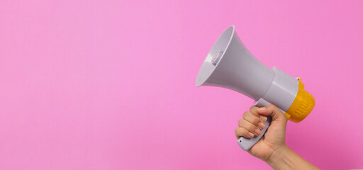 Hand is hold megaphone on pink background..