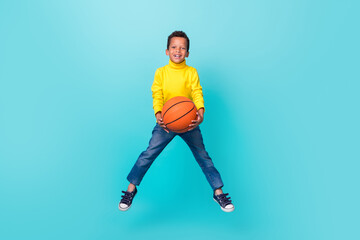 Fototapeta na wymiar Full length photo of excited sportive person jumping arms hold basketball isolated on turquoise color background