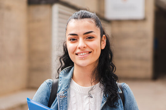 Pretty Hispanic Female Student Smiling And Looking At Camera In The High School. Head Shot Portrait Of Latin Teenager Girl Standing Outdoors At The University Campus. Education Concept. High Quality