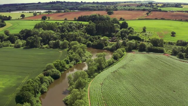 A brown muddy river winding through the British countryside