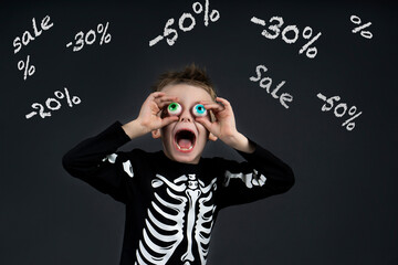 shocked little halloween boy with toy eyes looking up and at sale sale -50% -30 -20% open mouth with crazy and delighted in halloween costume skeleton on dark background sale concept. black friday kid
