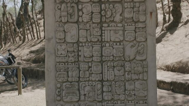 Quick camera pan down of a giant rock that has Mayan hieroglyphics carved into the front of it.