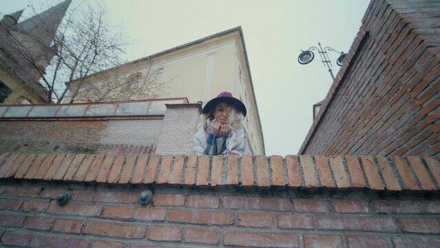 Female tourist on the top of stairway following the camera and showing her tangue. City view of buildings and stairway.
