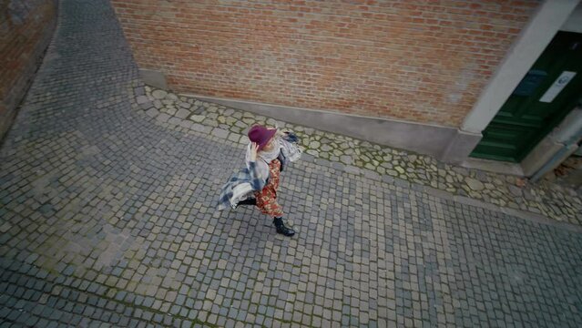 Top View Of Woman Running Away From Somebody Through A Brickwall Pathway. Female Being Followed In A City, She Happily Running And Smiling.