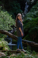 Young woman after a rock climb watching and exploring waterfall in Wicklow Mountains in sunny day,...