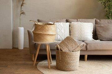 Various wicker baskets for interior decoration stand on the floor in a modern living room.