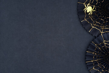 Spider and cobweb Halloween decoration background. The scary Halloween paper fans with gold cobwebs as a border on a dark textured background. Halloween theme with copy space.