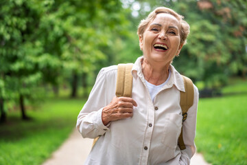 Portrait of beautiful happy caucasian active elderly woman enjoying nature walking in park. Active...