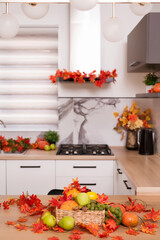 Autumn kitchen interior. Red and yellow leaves and flowers in the vase and pumpkin on light background