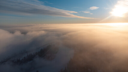 Fototapeta premium Sunrise breaking through the thick white fog at the top of Vuokatti Hill, a ski resort in Vuokatti, Finland. The Scandinavian experience of winter. Morning fog lingers over the Finnish tundra