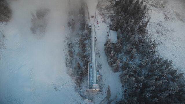 Sunrise breaking through the thick white mist at the top of Vuokatti Hill, a ski resort in Vuokatti, Finland. A view of the old ski jump. A Scandinavian winter experience