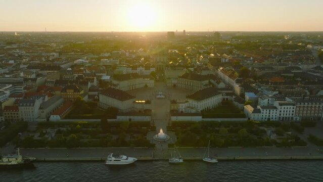 Aerial descending footage of royal Amalienborg palace and silhouette of Frederiks Kirke dome against setting sun. Copenhagen, Denmark