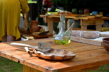 A close up on a medieval wooden table with some spoon and bowl made out of wood and with a vial full of olive oil or some other condiment seen during a medieval fair or festival organized in Poland