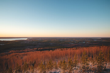 Breathtaking sunset on Mount Kivesvaara in Paltamo, Finland. View of the untouched forest landscape and Lake Kivesjarvi. Scandinavian scenery