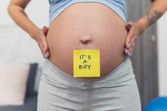 Close up baby bump of a pregnant woman with a sticker on it with the words - its a boy. Gender reveal concept. High quality photo