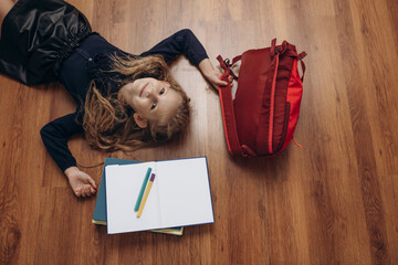 Beautiful girl child - schoolgirl with books, notebook, pens and backpack, portrait on the floor,...