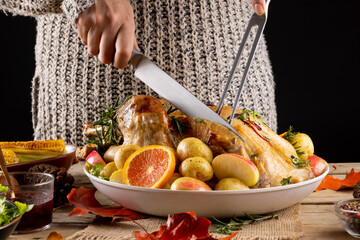 Close up of caucasian woman carving thanksgiving roast turkey with vegetables