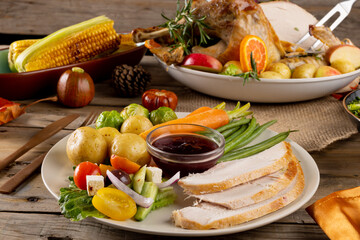 Obraz premium Overhead view of thanksgiving plate of roast turkey with vegetables on wooden background