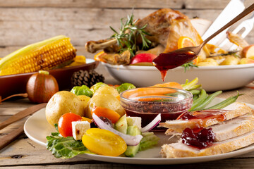 Obraz premium Close up of plate of thanksgiving roast turkey with vegetables on wooden background
