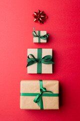Image of christmas gifts and red star forming christmas tree and copy space on red background