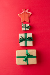 Image of christmas gifts and red star forming christmas tree and copy space on red background
