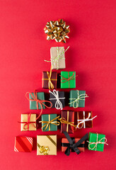 Image of christmas gifts forming christmas tree and copy space on red background