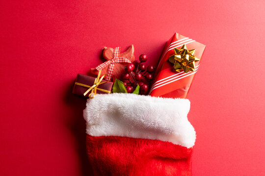 Image of christmas gifts in christmas stocking and copy space on red background