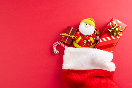 Image of christmas gifts and santa claus in christmas stocking and copy space on red background
