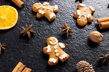 Image of gingerbread man cinnamon sticks and christmas decoration on black