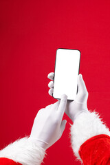 Image of hands of santa claus holding smartphone with blank screen and copy space on red background