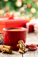 Image of gingerbread man, red cup, cinnamon sticks and christmas decoration on wood