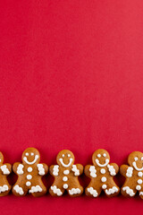 Image of row of christmas gingerbread man biscuits with copy space on red