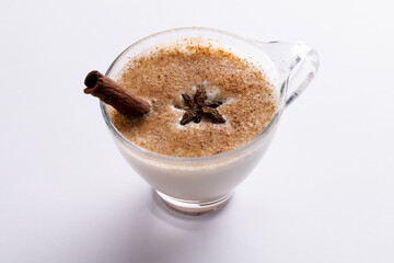 Image of glass of christmas milk with cinnamon stick, anise star and copy space on white background