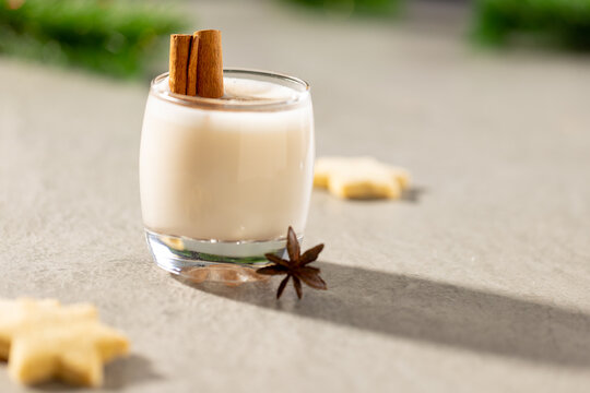 Image of glass of milk with cinnamon and christmas decorations with copy space on grey