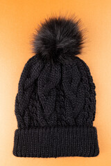 Vertical image of wool beanie with pom pom on yellow surface