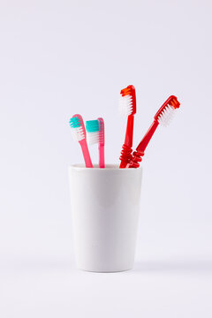 Vertical image of toothbrushes in cup on grey background