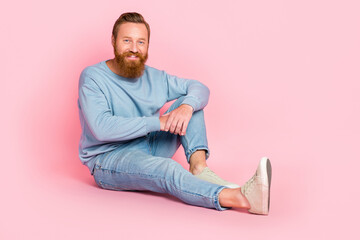 Full body photo of satisfied friendly person sit floor toothy smile isolated on pink color background © deagreez
