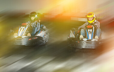 active young man and women competing on racing cars at kart circuit © JackF