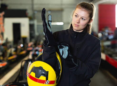 positive sportive woman puts equipment for karting in sport club