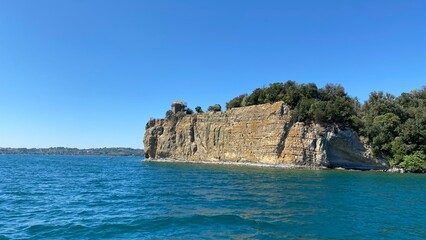 island in the Bolsena lake on a sunny summer day in the Lazio region of Italy with blue sky and rocky cliff