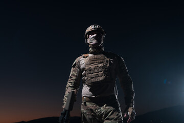 Army soldier in Combat Uniforms with an assault rifle, plate carrier and combat helmet going on a...