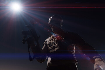 Army soldier in Combat Uniforms with an assault rifle, plate carrier and combat helmet going on a dangerous mission on a rainy night. 