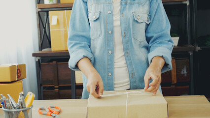 Woman packing box on table checking goods package delivery shipping to customer. Asian woman startup small business at home office desk. Entrepreneur asian woman packing product for delivery items