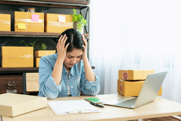 Desperate Asian woman stress headache depressed from startup small business at home office. Failure business woman work at home office. Online seller entrepreneur has problem delivery unhappy job